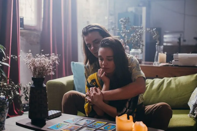 Tirada de tarot pareja: cómo hacerla y cómo leerla Pareja haciendo una tirada de tarot pareja sobre una mesa de madera