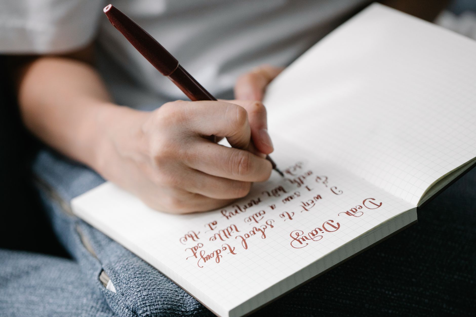 Carta a tu yo futuro: guía simbólica Persona escribiendo a mano en un cuaderno apoyado sobre sus piernas