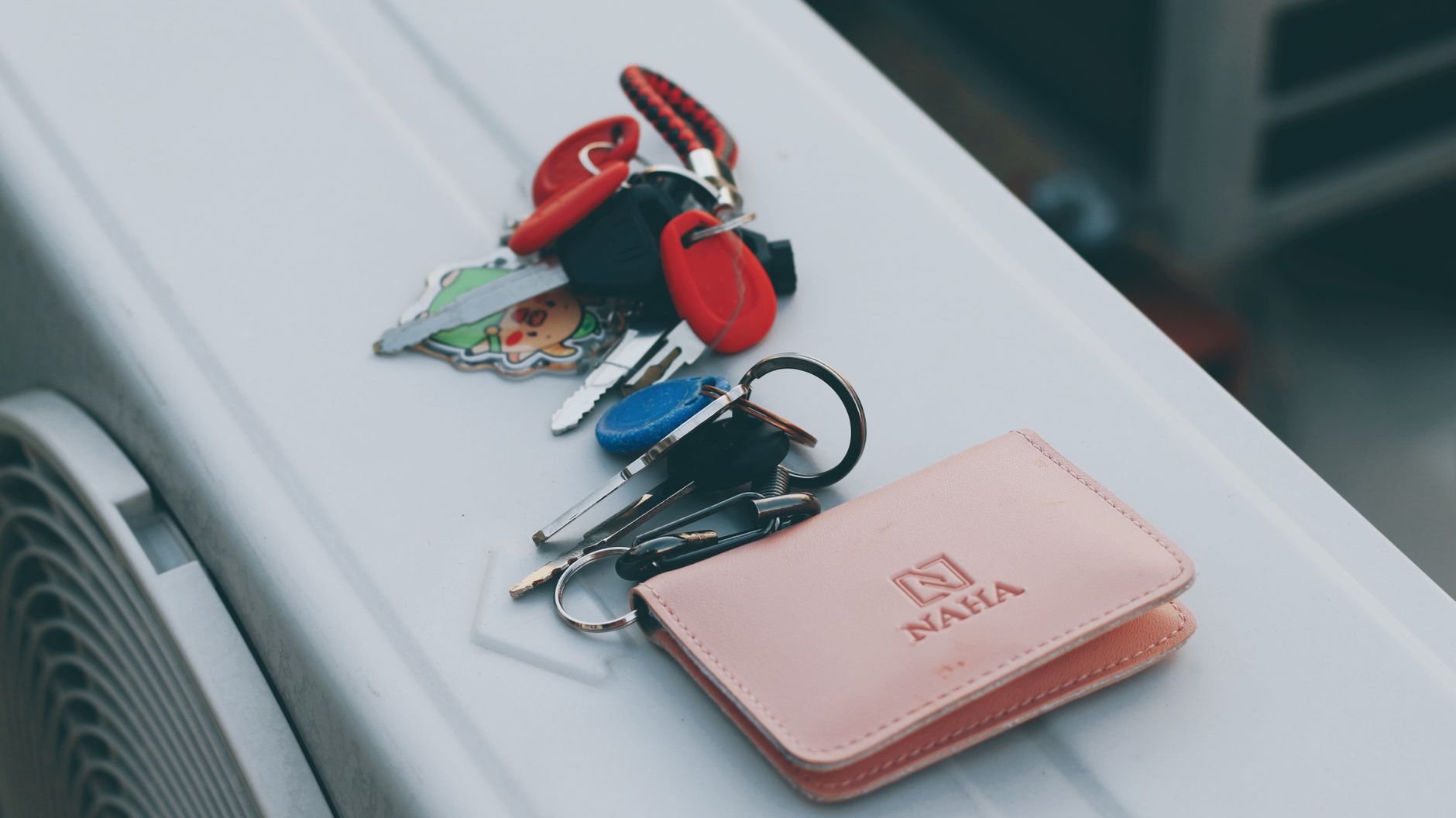 Cómo limpiar objetos personales de energía Llaveros con varias llaves junto a una cartera rosa sobre una mesa blanca