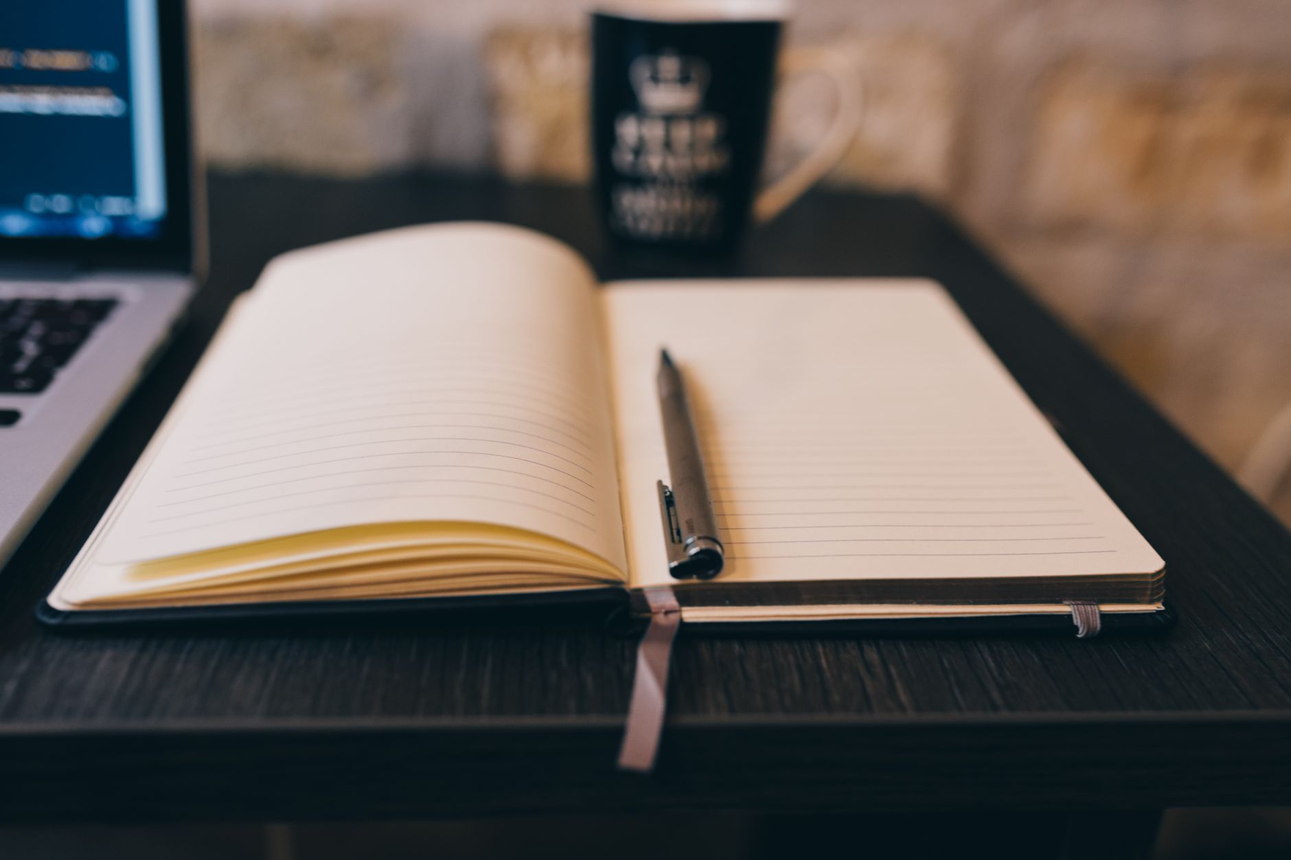 Cómo crear un rincón de reflexión en casa Cuaderno abierto con bolígrafo sobre una mesa junto a un portátil